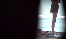 Nudista rubia desnudándose en la playa