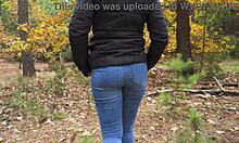 穿着蓝色牛仔裤的少女女友在树林里挑逗性地暴露出她结实的屁股